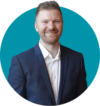 Smiling man with short light brown hair wearing a dark blue suit and white shirt against a teal circular background.