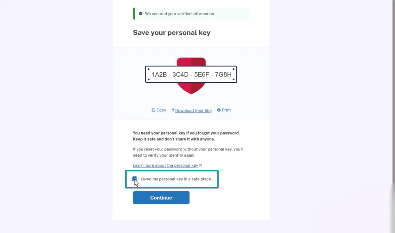 Screen showing a message that verified information is secured and instructing to save a personal key displayed as '1A2B - 3C4D - 5E6F - 7G8H' above an icon of a red shield. Options below the key include Copy, Download (text file), and Print. Text explains the importance of keeping the personal key safe to reset a password and verify identity. A checkbox labeled 'I saved my personal key in a safe place' is shown with a cursor hovering over it, and a blue Continue button is below.