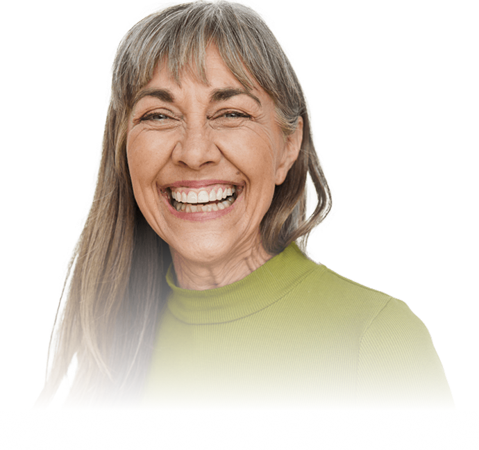 Smiling older woman with long gray hair wearing a light green turtleneck shirt.