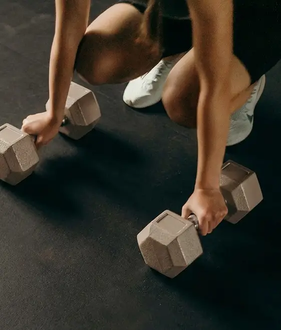 Two hands picking up a pair of dumbbells