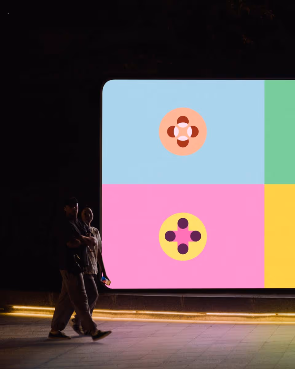 Light-up Teak brand billboard in a dark dramatic lighting featuring a colorful quadrant design with geometric flower patterns and logo