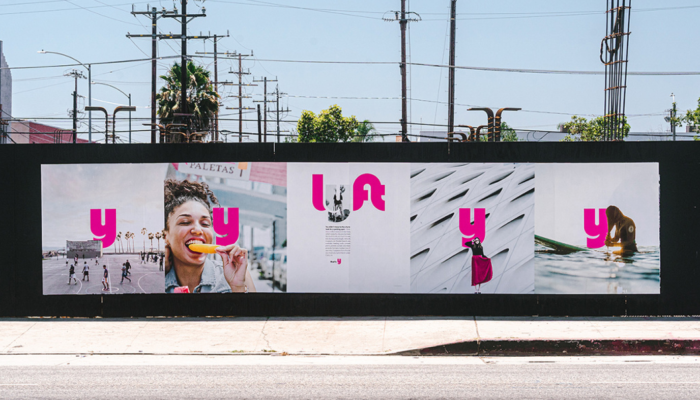Roadside billboard with pink Lyft Y branding along a city street