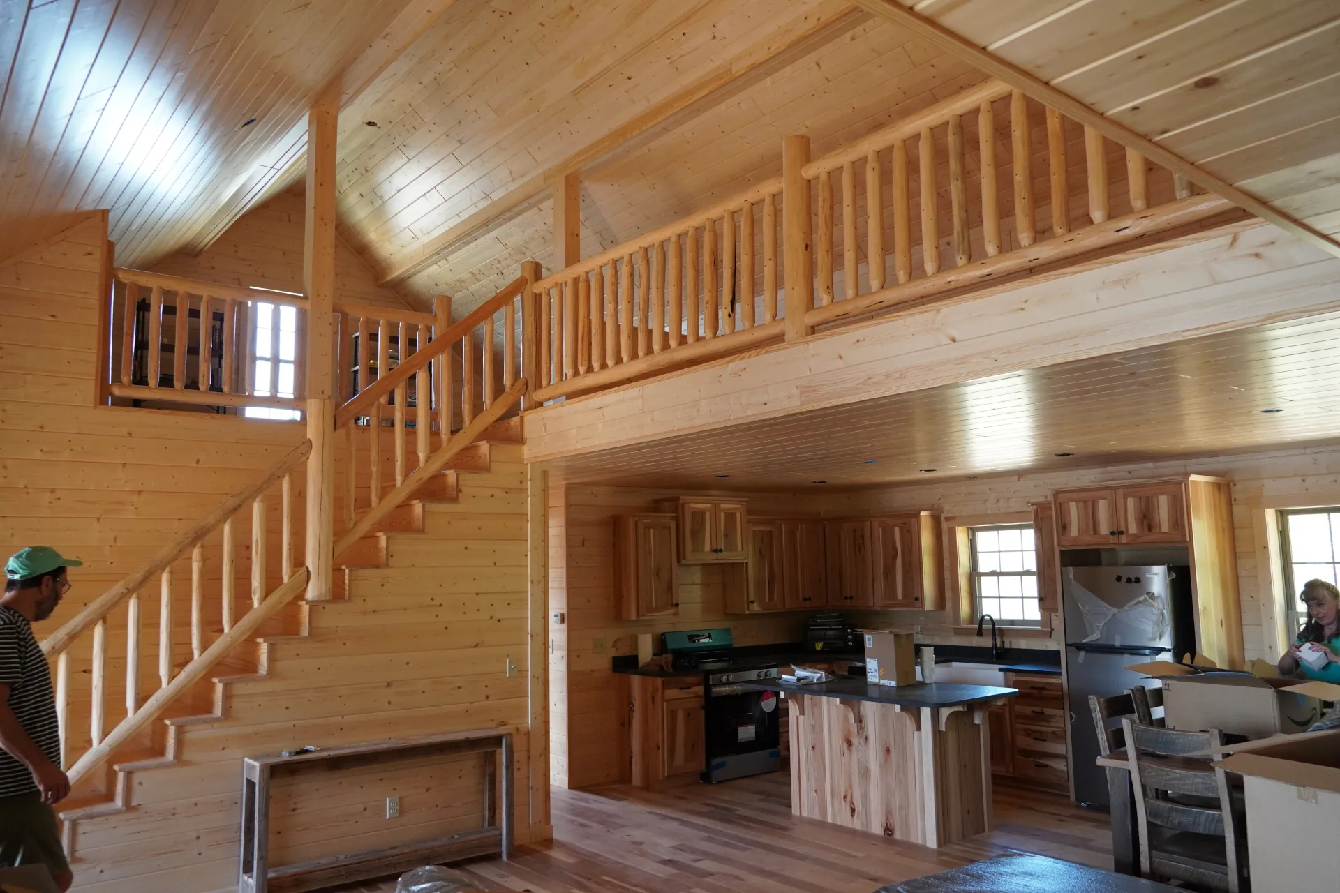 inside view of 2 story tiny home with a kitchen in the bottom and a lofted space above, all made of exposed wood planks