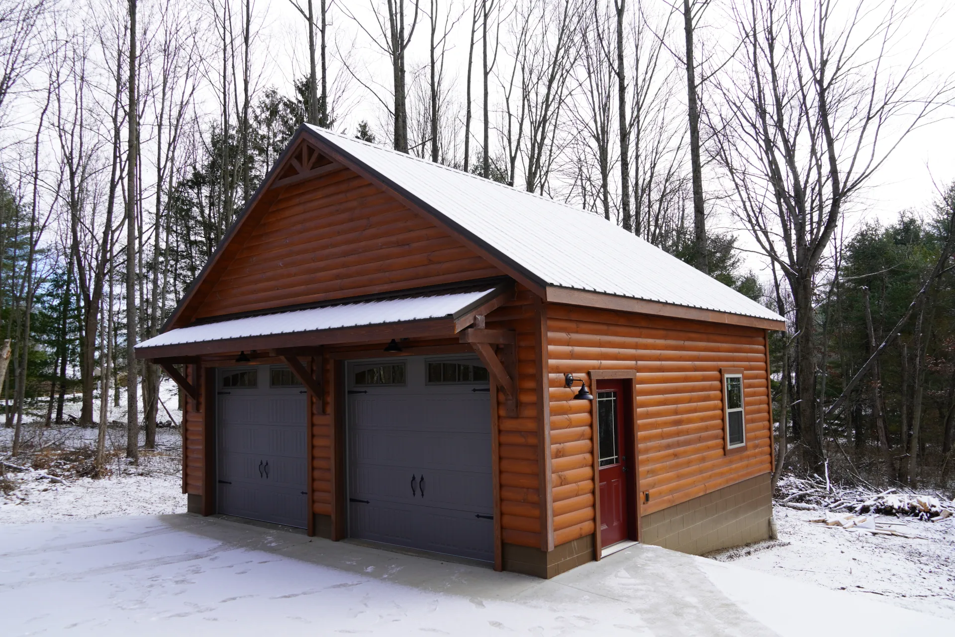 A small wooden cabin with 2 garage doors and a side man door