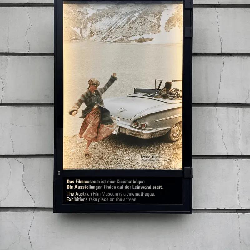 A poster depicting a boy in a jacket dancing behind a vintage sports car.