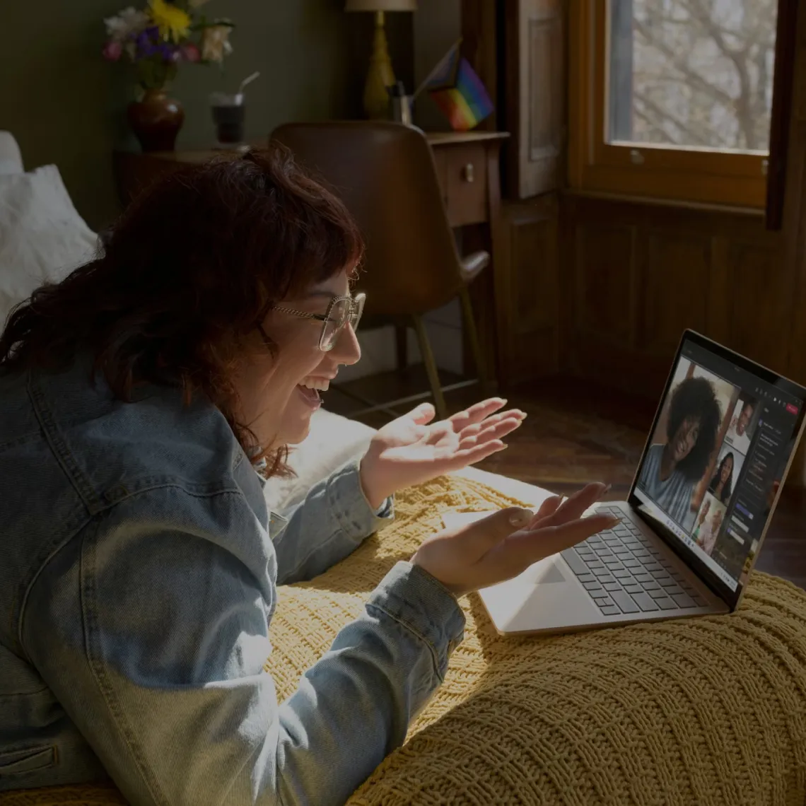 A girl lying on a sofa while having a video call with other people.