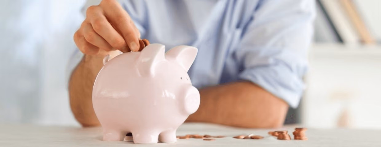 man putting money in piggy bank