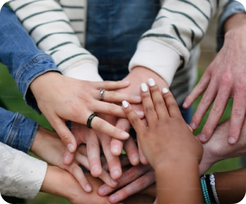 Multiple diverse hands stacked together in a gesture of unity and teamwork.