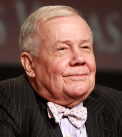 Older man in a pinstripe suit and floral bow tie, smiling slightly with eyes closed.