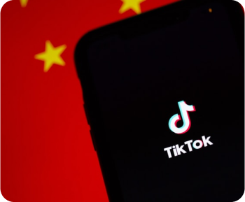 Smartphone displaying the TikTok logo on screen with a blurred red background featuring yellow stars resembling the Chinese flag.