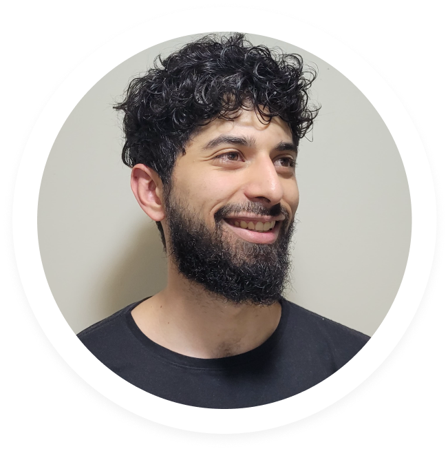 Smiling man with curly black hair and beard wearing a black shirt, looking to the right.