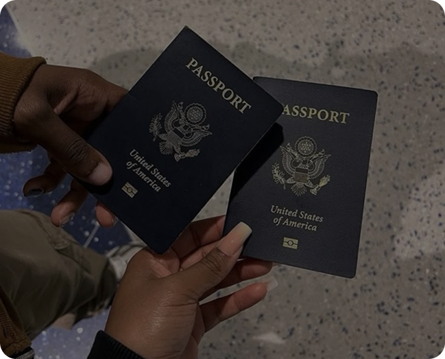 Two hands holding United States passports with the blue cover and eagle emblem.