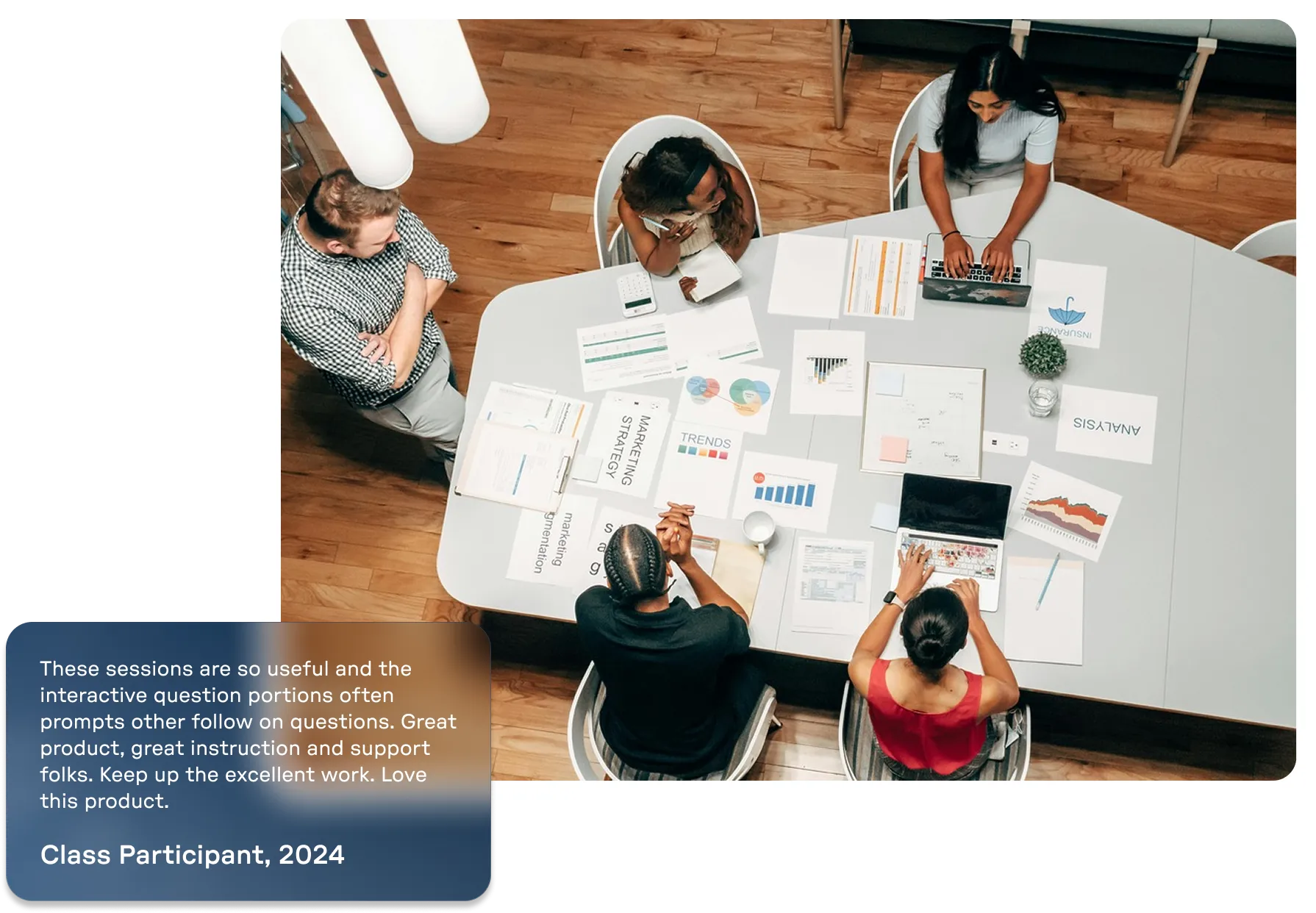 Overhead view of four diverse people collaborating around a table covered with charts, documents, laptops, and notebooks in a meeting room.