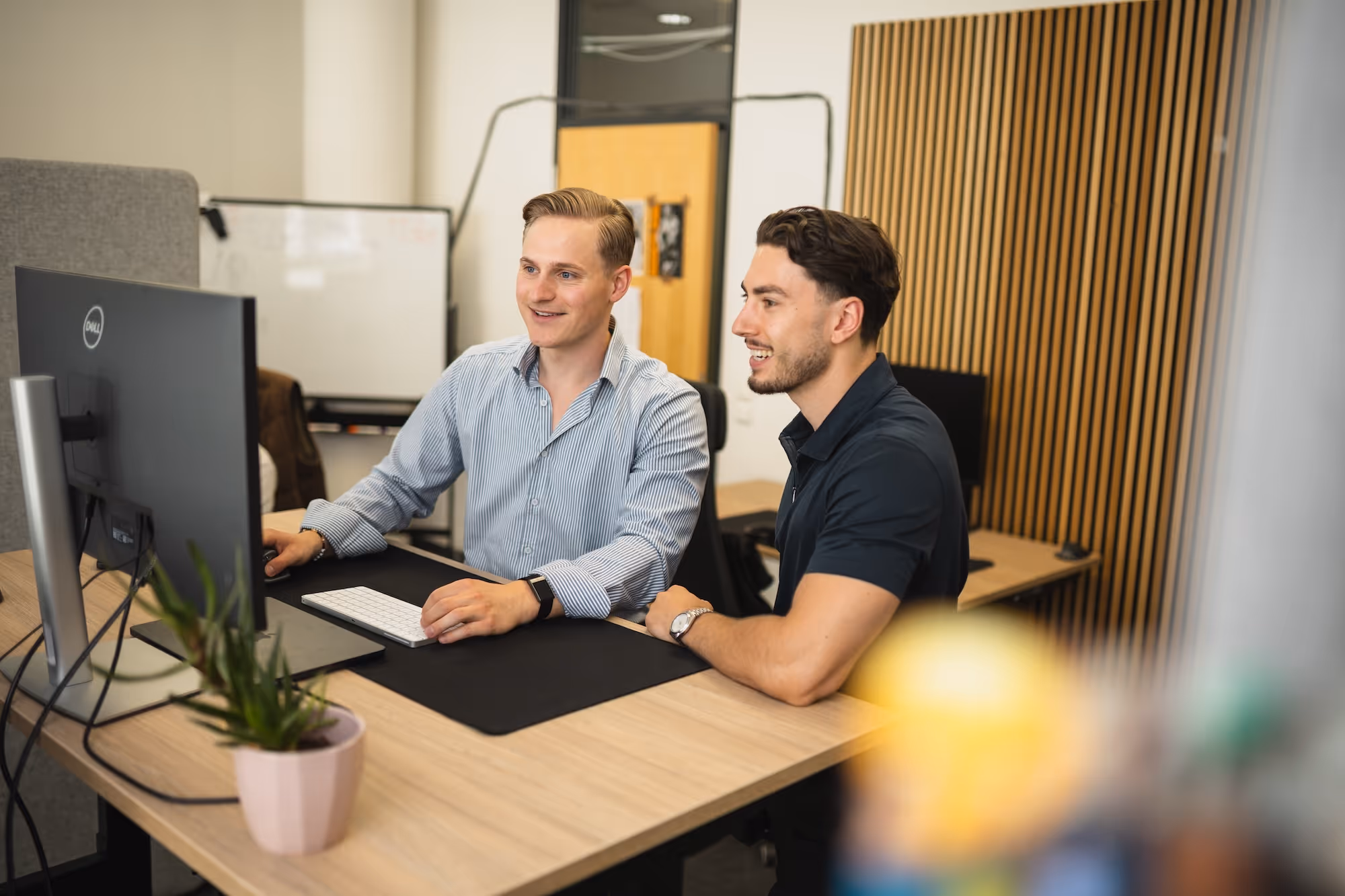 Zwei Männer arbeiten zusammen an einem Computer in einem modernen Büro.