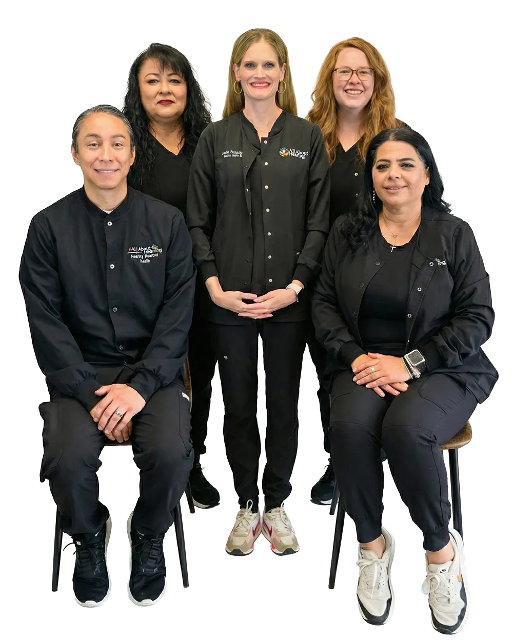 Group of four people, two sitting and two standing behind, all wearing black clothing and smiling at the camera.