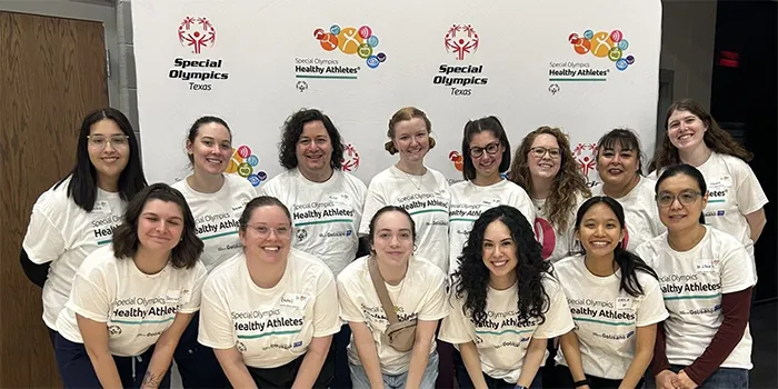 Person with gray hair wearing a hearing test device seated facing a machine in a clinic room.