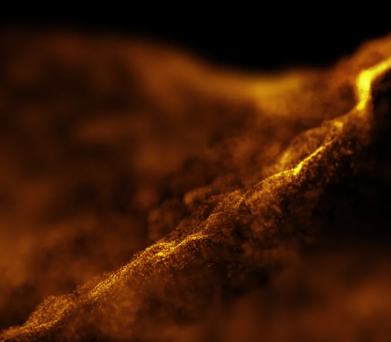 Abstract close-up of glowing golden particles forming a flowing wave on a dark background.