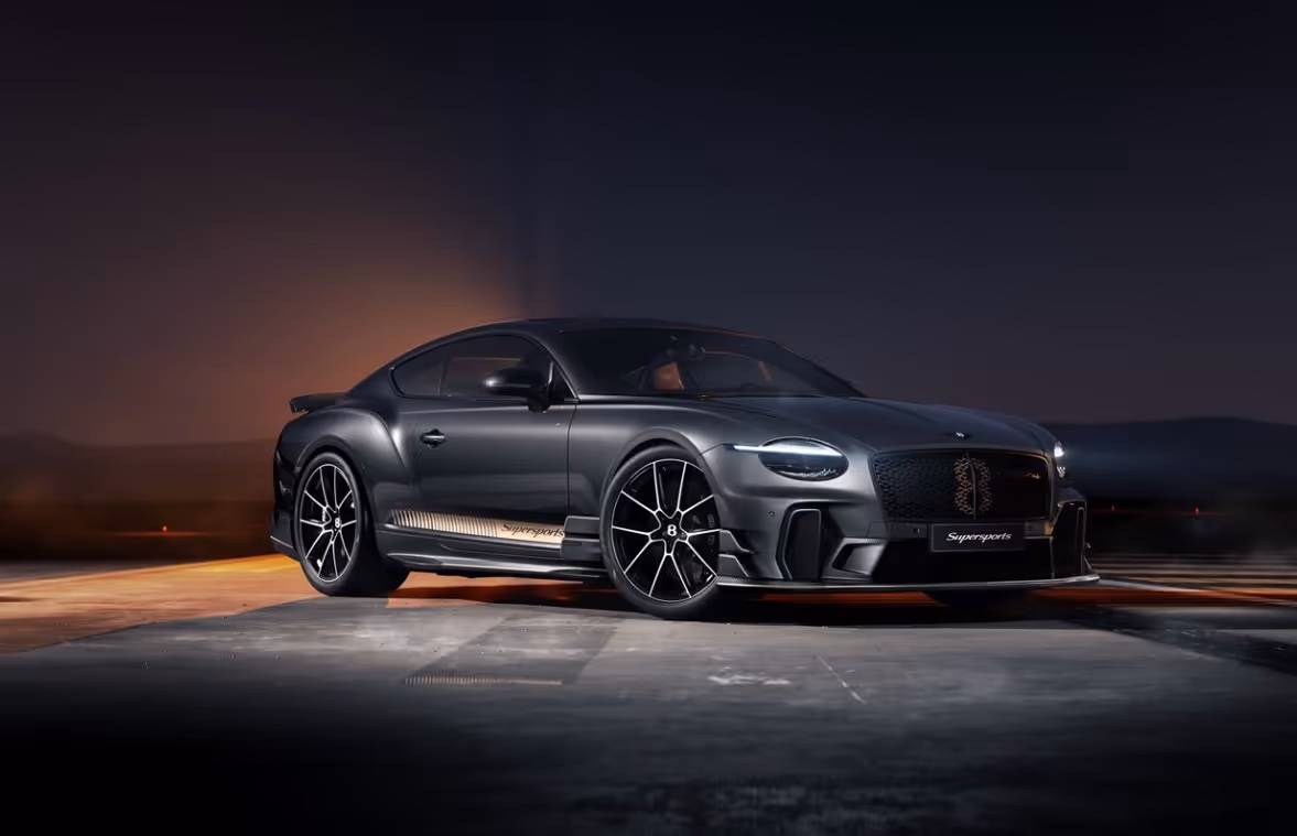 Sleek black Bentley Continental Supersports parked on an empty road at dusk with headlights on.