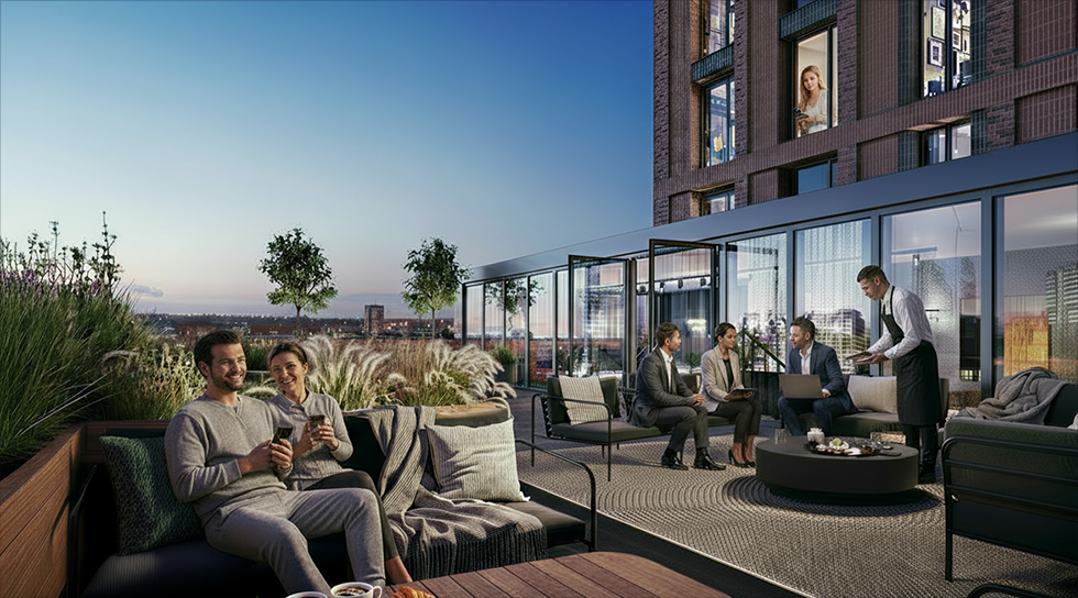 Two people sitting on an outdoor sofa enjoying drinks while three business professionals consult together nearby with a waiter serving at a rooftop terrace during dusk.