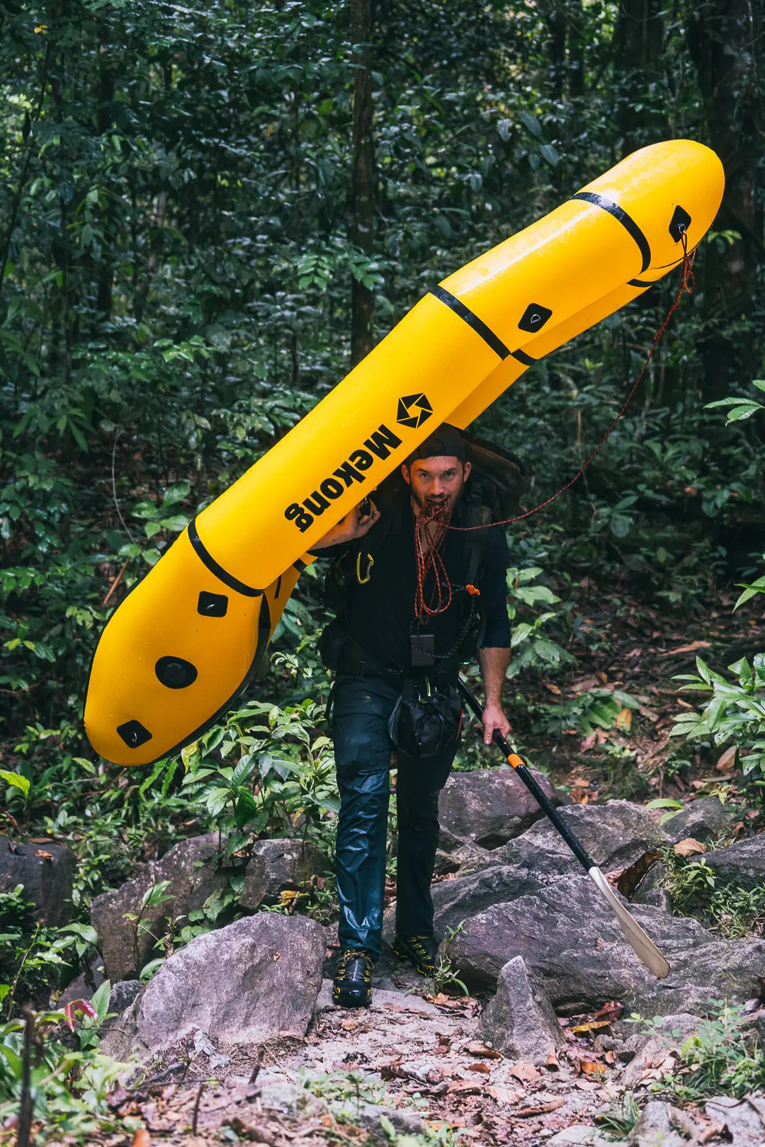 Homme portant un packcraft Mekong, sur le dos, dans la forêt