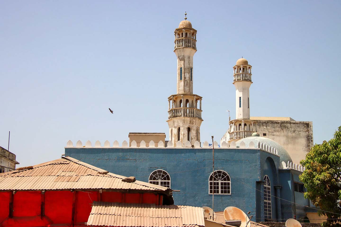 Blue mosque building with two ornate minarets and a dome under a clear sky in Banjul.