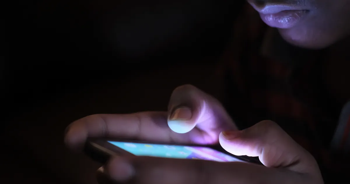 A hand holding a smartphone with a mobile browser open on the address bar