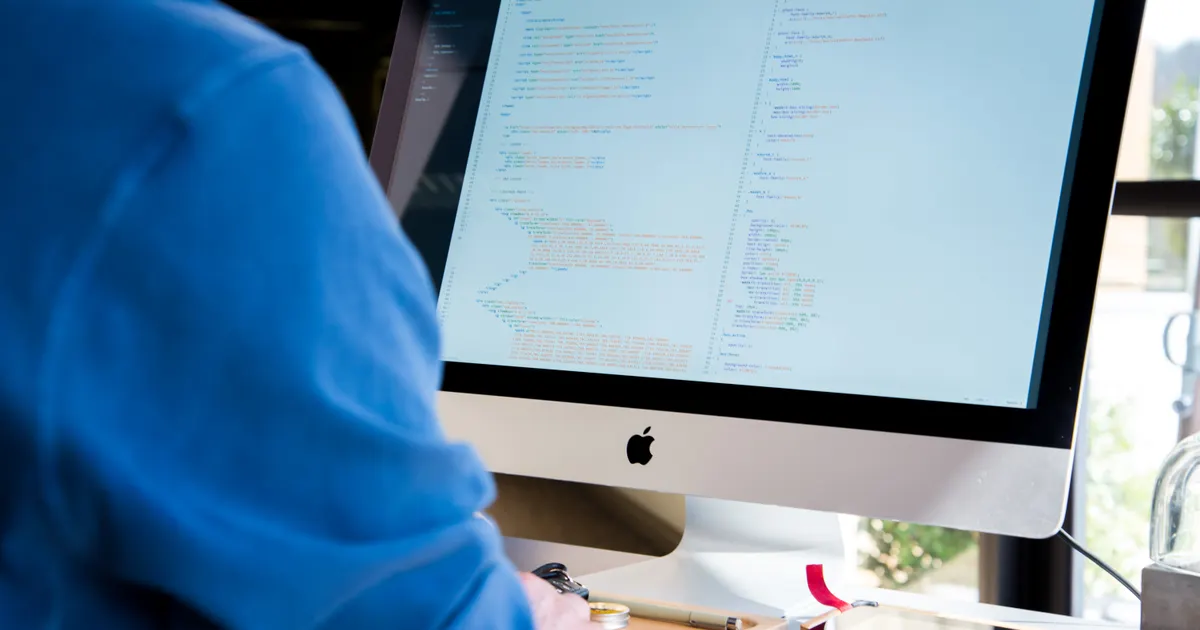 A software developer writing code at a computer workstation