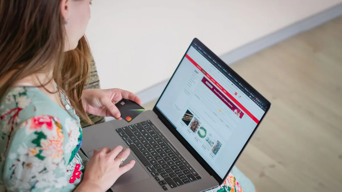 Woman shopping online on a laptop with a bank card, illustrating the ranking of the best e-commerce agencies in France