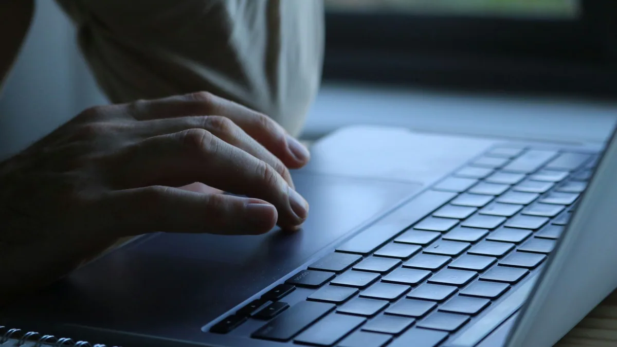 Hands typing on a laptop keyboard in an office, illustrating the ranking of the best cold email agencies in France