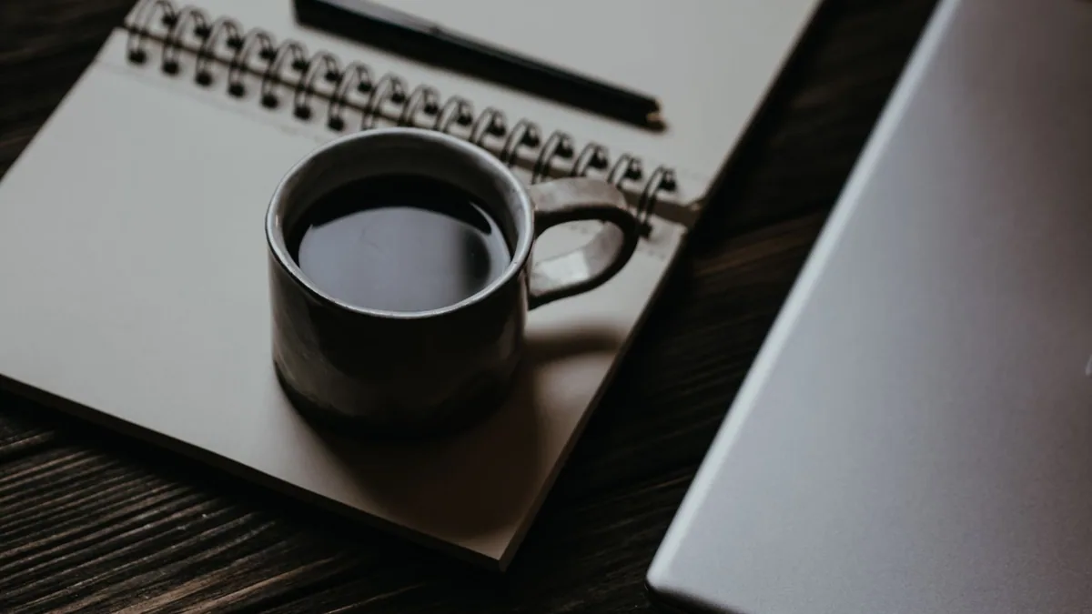 Carnet, tasse de café et ordinateur portable sur un bureau d'écriture, illustrant le classement des meilleures agences de contenu en France