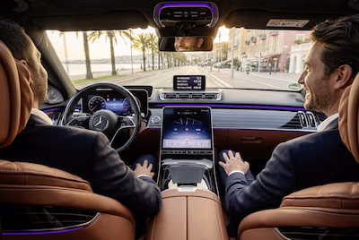 Chauffeur Dixi VTC conduisant une Mercedes Classe S le long de la Côte d’Azur, intérieur luxueux avec éclairage d’ambiance.