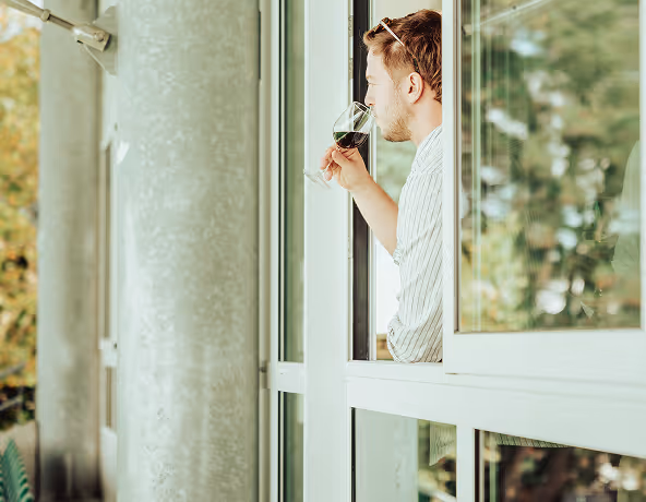 Personne observant l’extérieur depuis une fenêtre dans un espace intérieur du Stade Nantais.