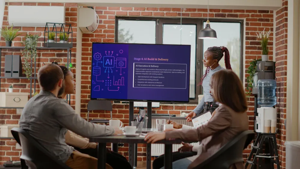 Business team in a modern office watching a presentation on AI Build & Delivery on a large screen.