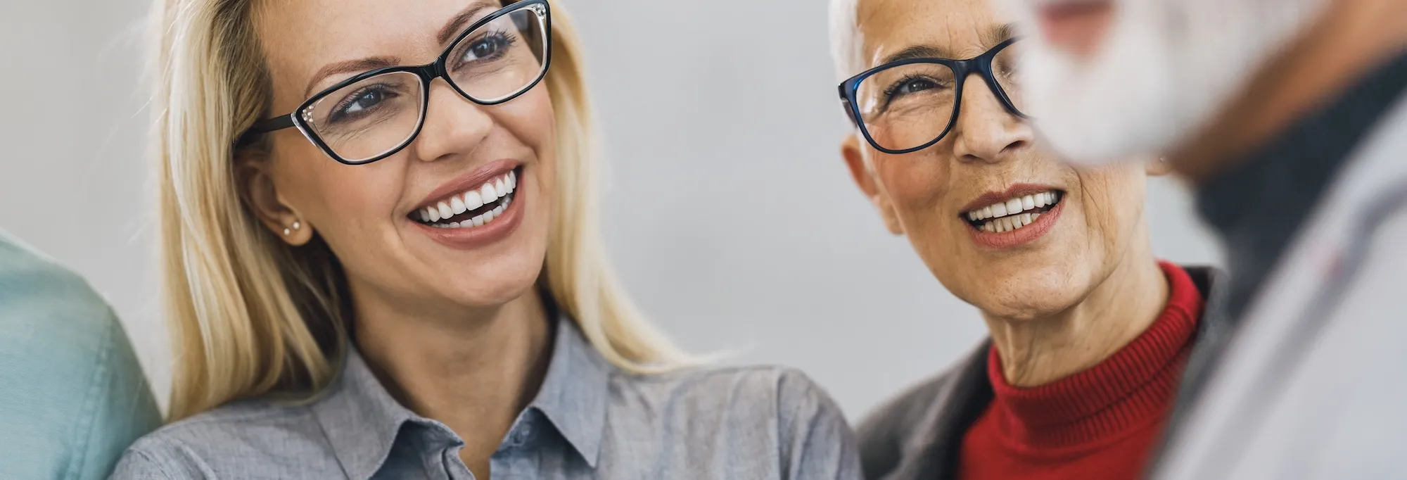 Two women with glasses smiling warmly at each other