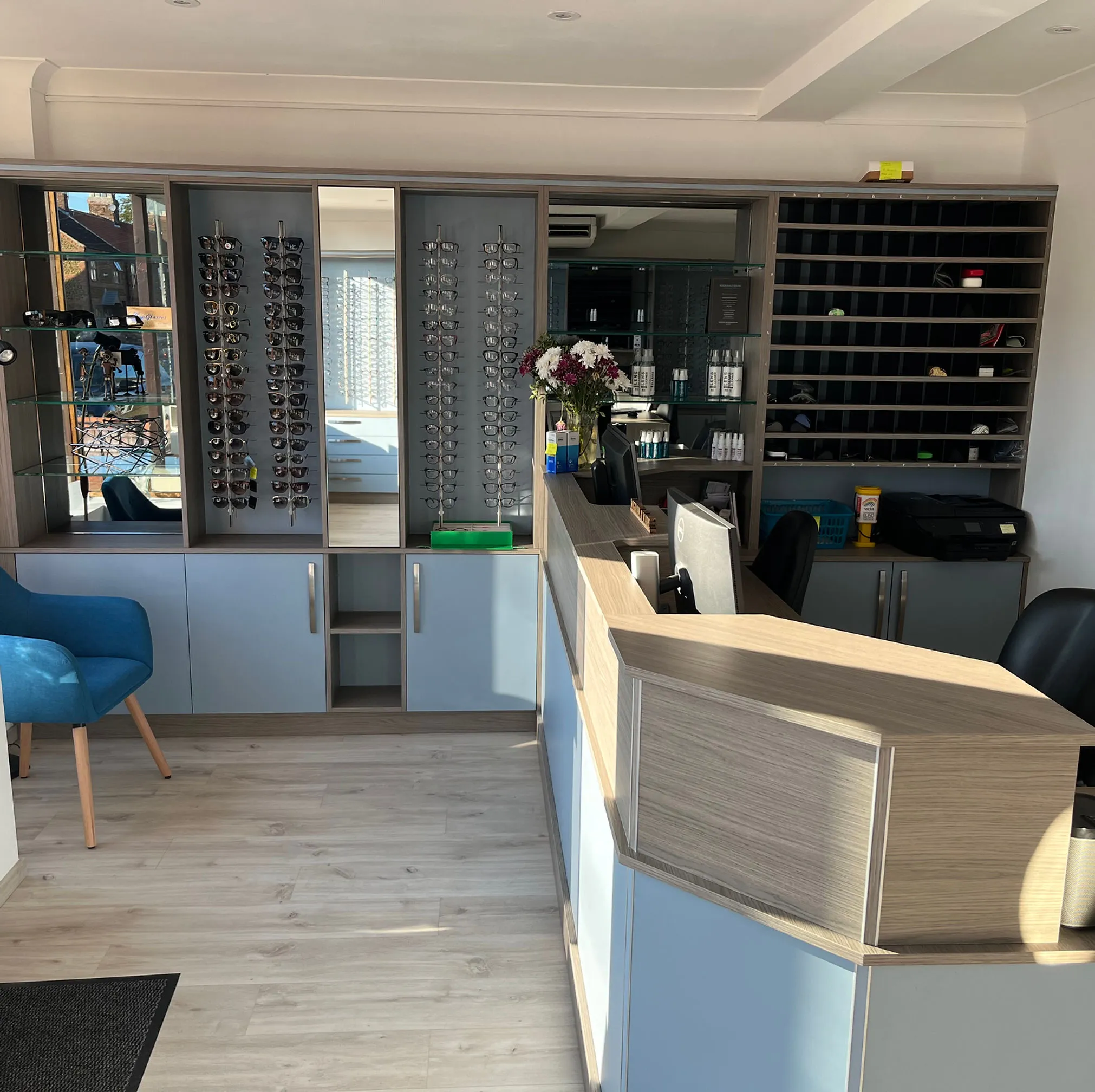 Optician's office with glasses displays, reception counter, and blue chair
