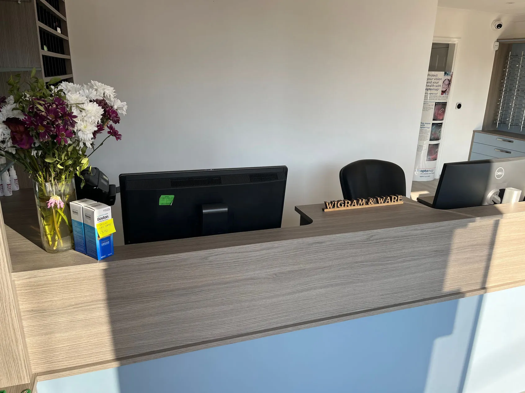 Reception desk with flowers, computer, and Wigram & Ware wooden sign