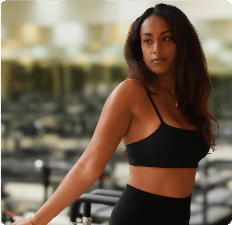 Vrouw in zwarte sportkleding in fitnessruimte.