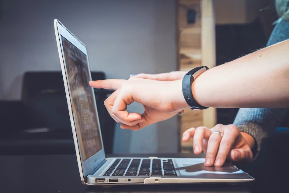 close up of hands pointing at a laptop screen