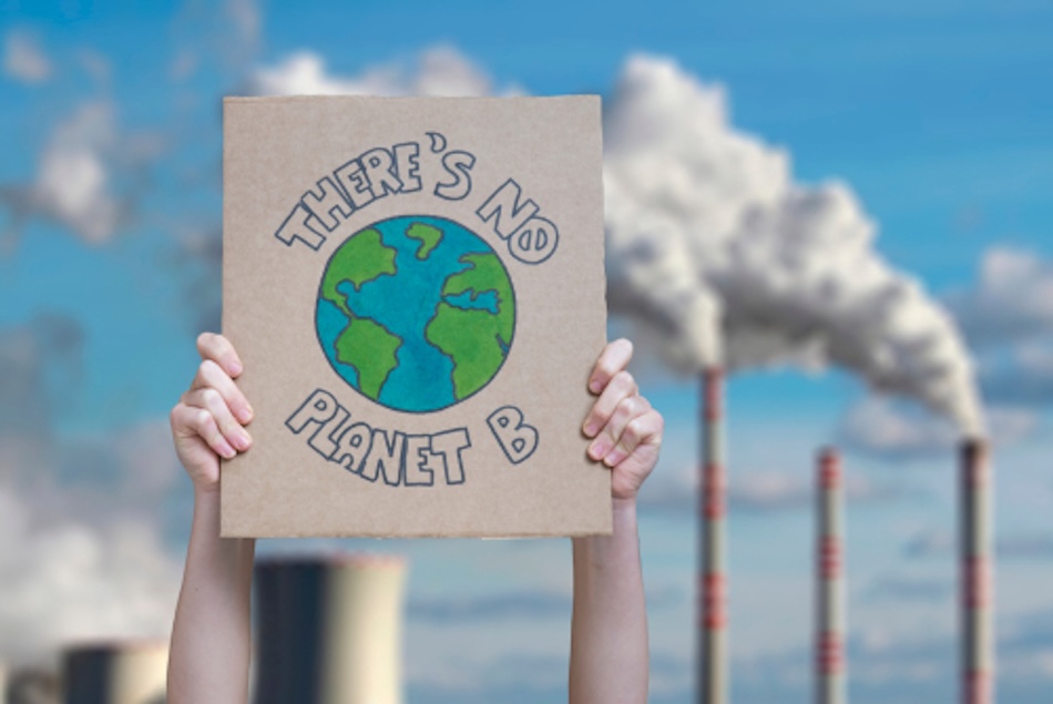 A person holds up a handdrawn sign that reads 'There's no planet B' with a picture of earth in the middle