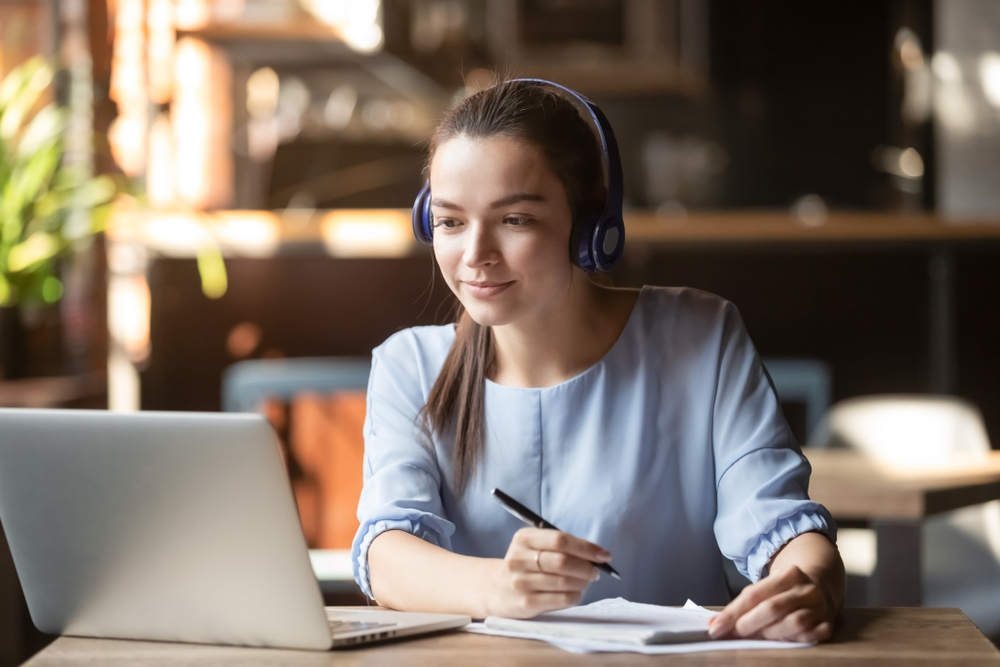 Young woman with headphones works at a laptop