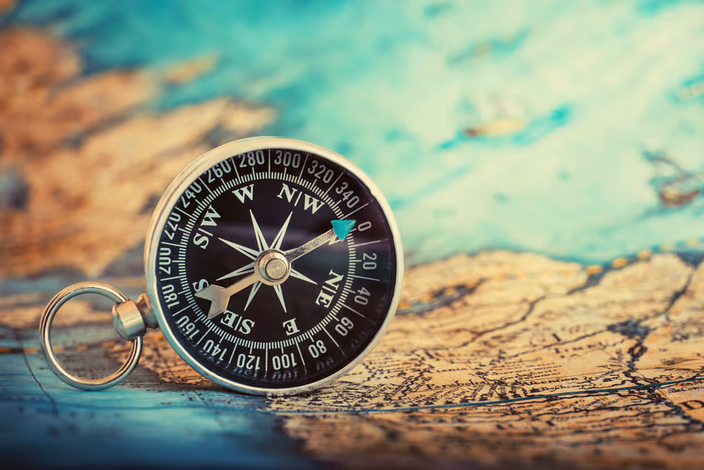A black compass sitting on top of a map