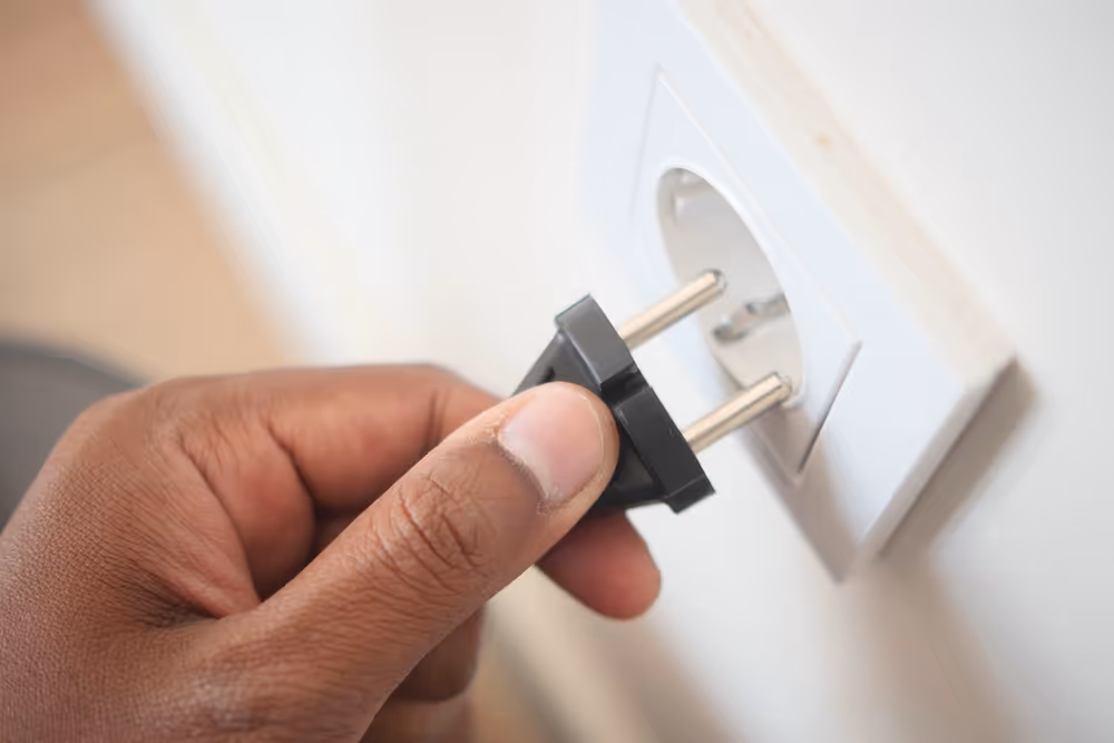 A man's hand putting an electrical plug into a socket