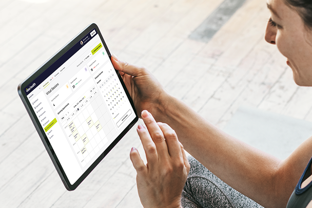 Person holding a tablet displaying a virtual session schedule with calendar and session details.