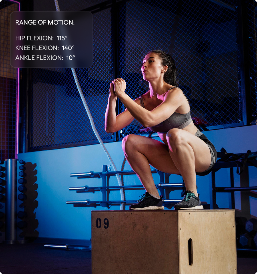 Woman in sportswear performing box squats on a wooden plyometric box inside a gym.