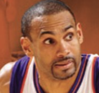 Close-up of a basketball player wearing a white jersey with blue and orange trim looking to the side.