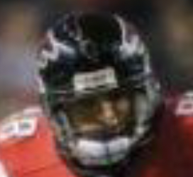 Blurred close-up of a football player wearing a black helmet and red jersey.