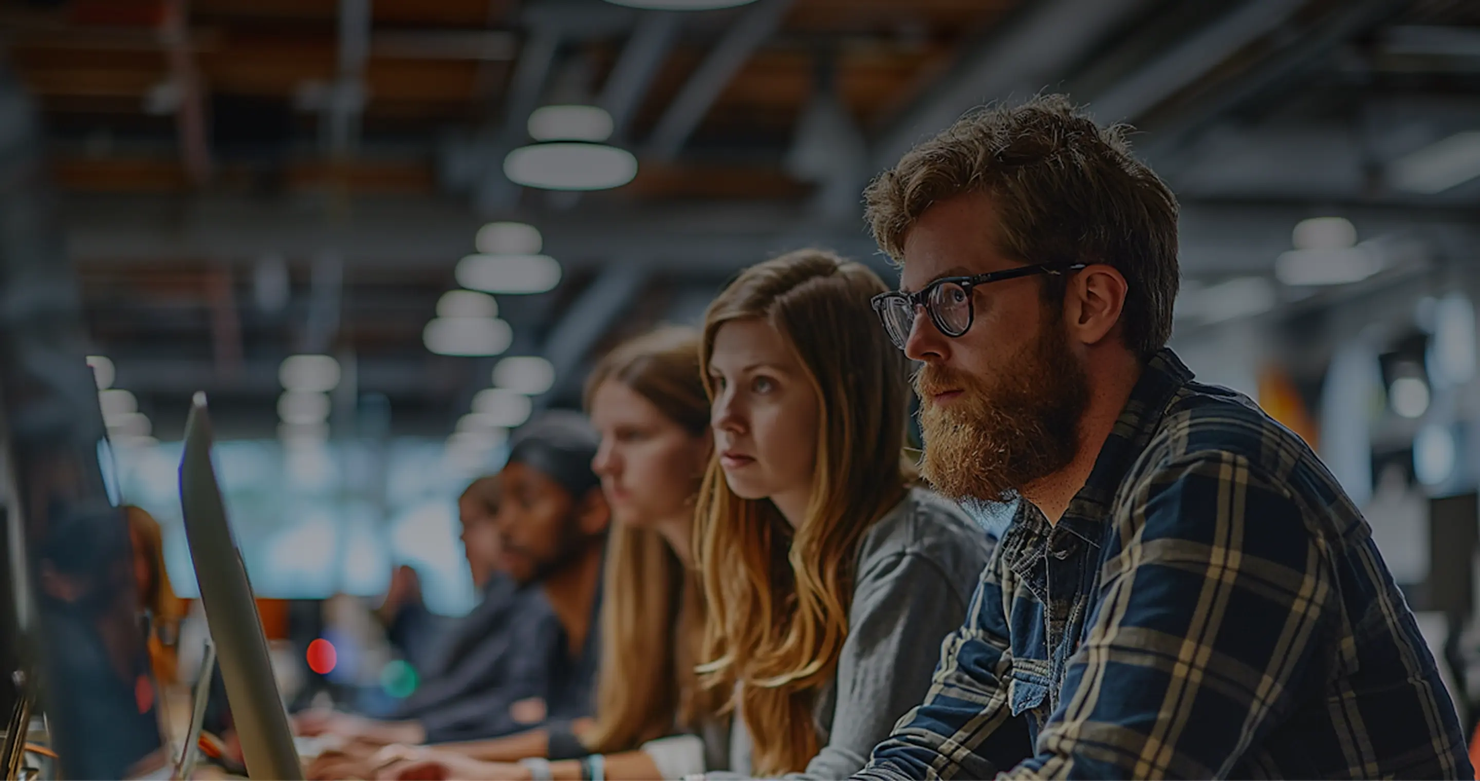 A group of young professionals focused on working at computers in a modern office space.