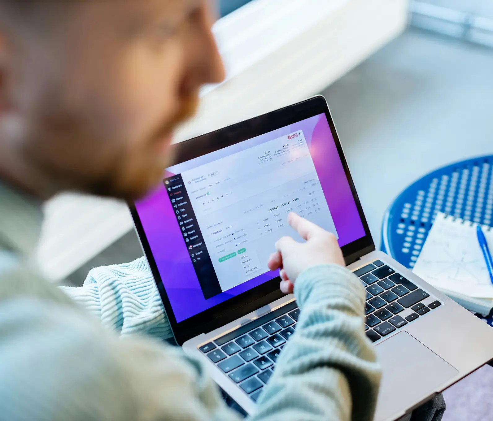 Person pointing at a laptop screen displaying a financial or project management dashboard with charts and data.
