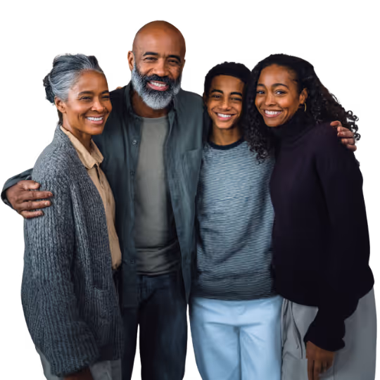 Smiling family of four standing close together with arms around each other.