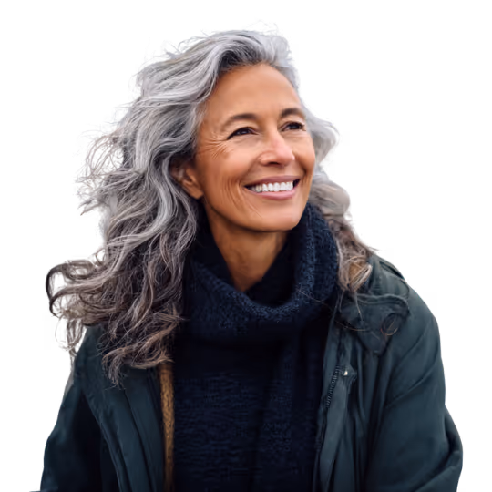 Smiling middle-aged woman with long wavy gray hair wearing a dark sweater and green jacket.